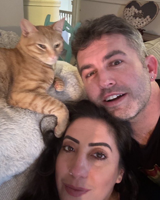 Lauren and Shawn on the sofa with the orange cat